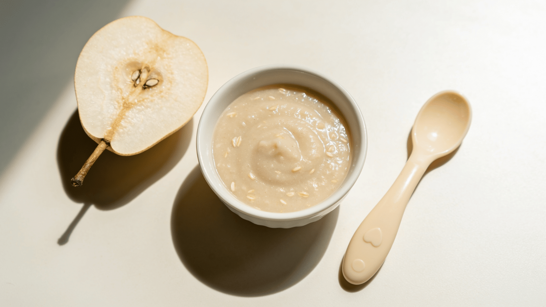 _smooth pale pear-and-oat puree in a small bowl with a baby spoon