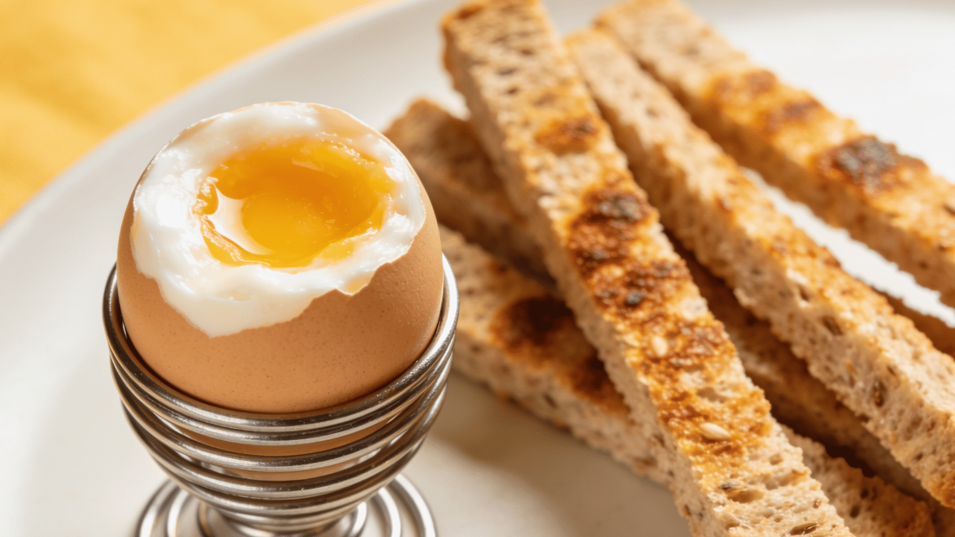 soft-boiled egg in a small egg cup with whole-grain toast strips arranged beside