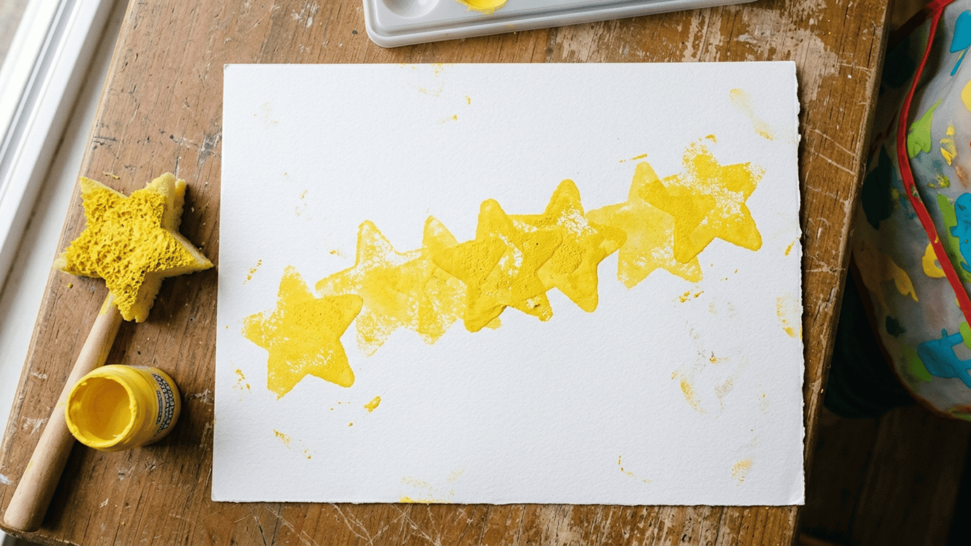 toddler painting with uneven row of stamped yellow stars