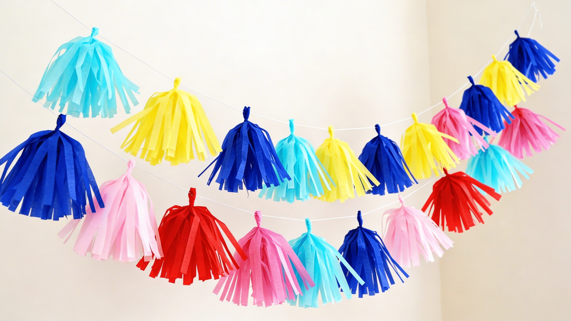 string of colorful tissue paper tassels evenly spaced along a hanging twine