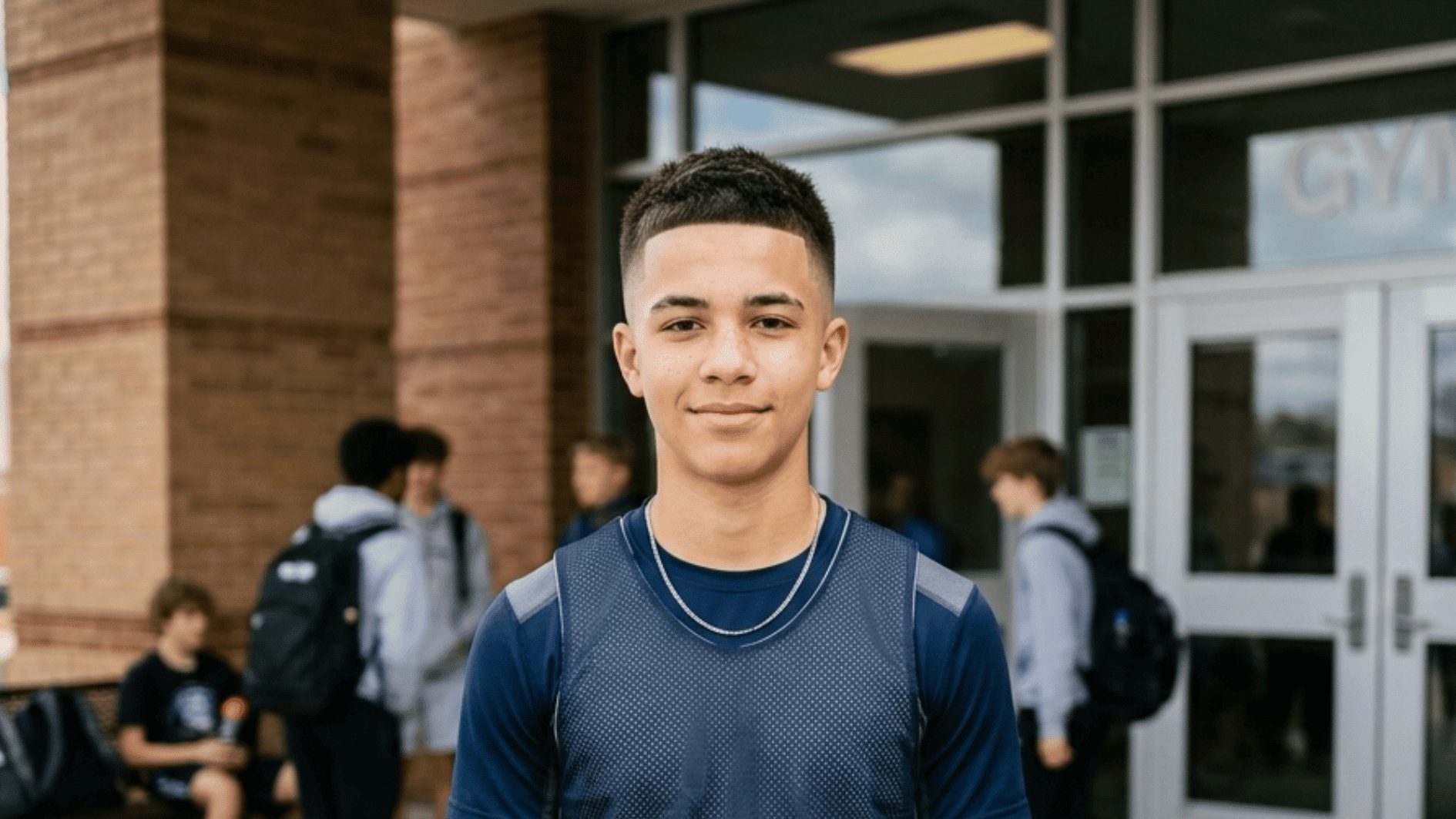 teen boy with clean crew cut fade haircut featuring short hair and blended sides near a school gym entrance