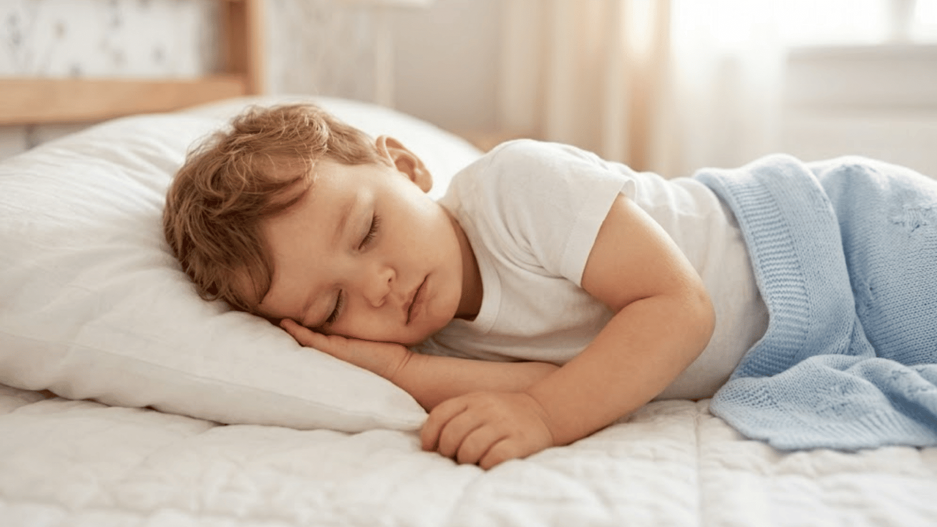 toddler sleeping peacefully on a pillow in bed with a soft blanket during bedtime rest