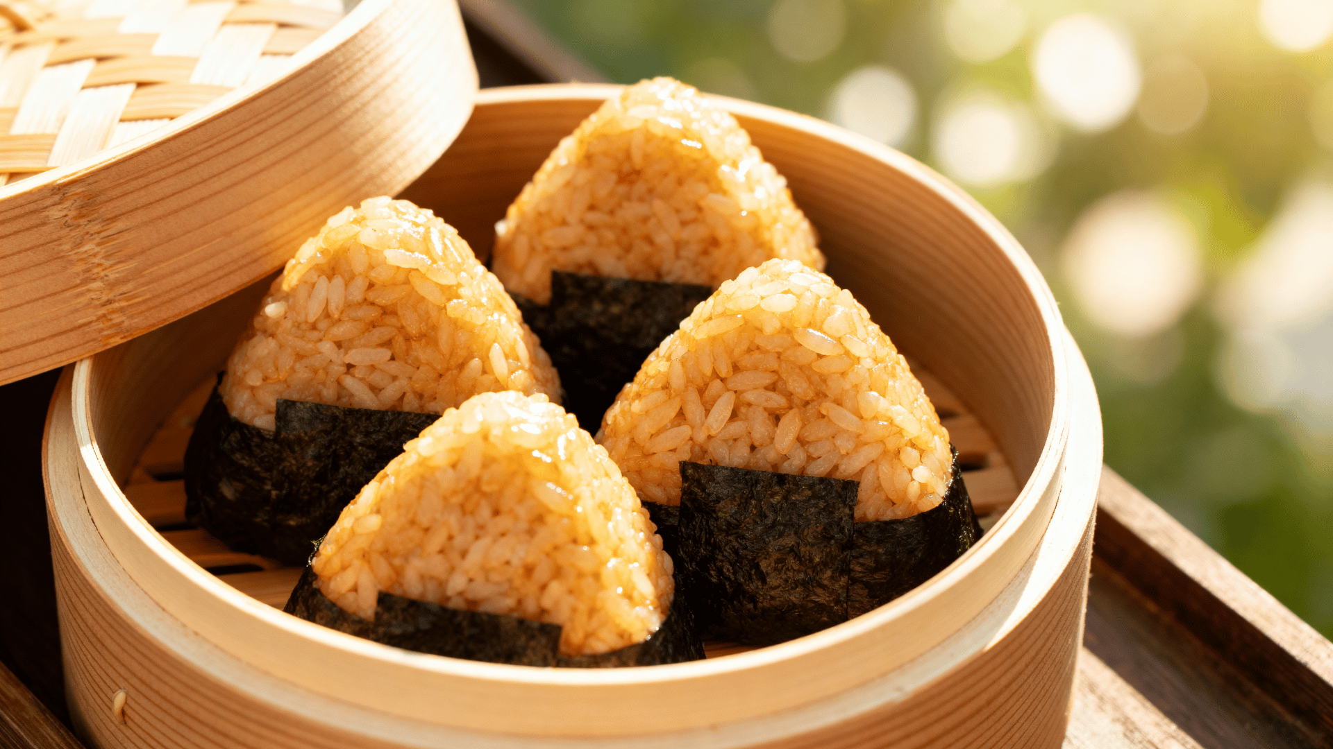 triangular rice balls wrapped in nori, packed in a round bamboo bento box