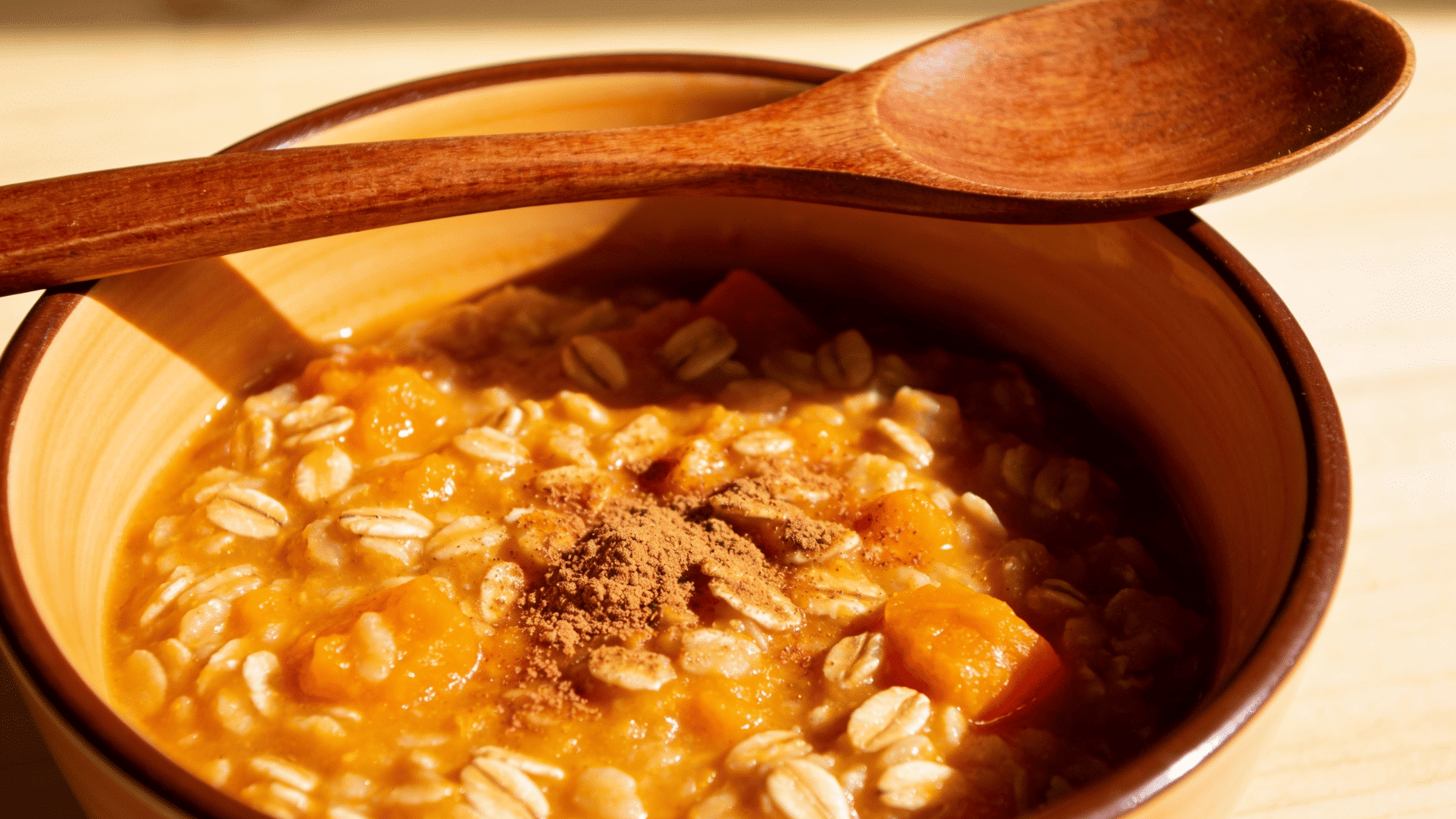 warm bowl of orange-tinted pumpkin oat porridge dusted with cinnamon