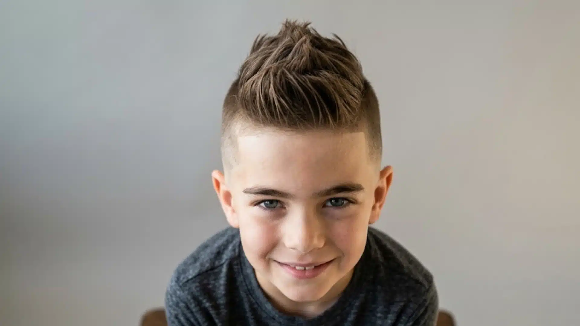 young boy with a faux hawk fade haircut featuring brushed up center spikes and closely faded sides