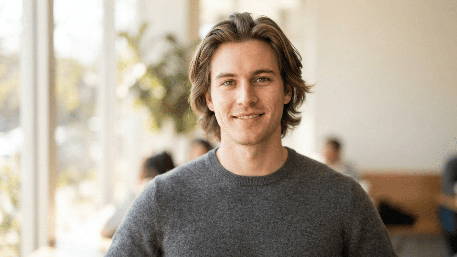 young man with a medium length flow haircut and natural layers in a casual indoor setting