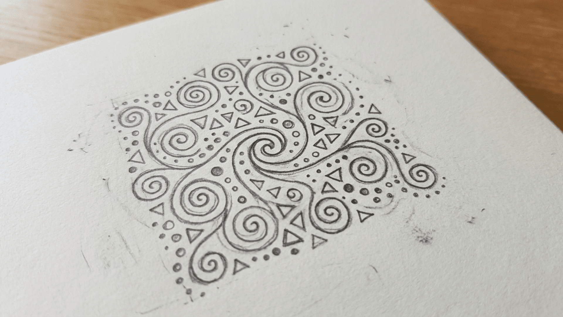 small pencil doodle filled with repeating swirls, dots, and triangles in a zentangle style
