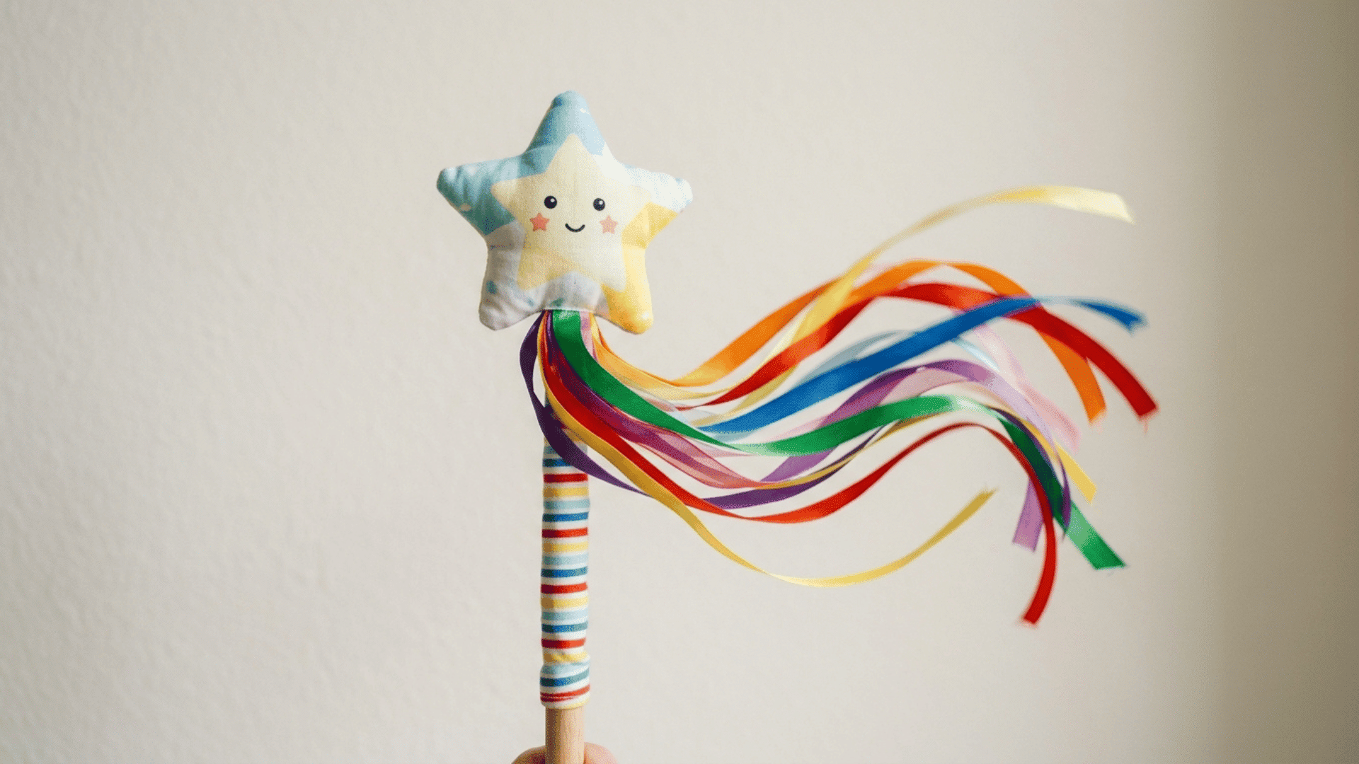 smiling fabric star wand with long colourful ribbons flowing against a simple neutral background