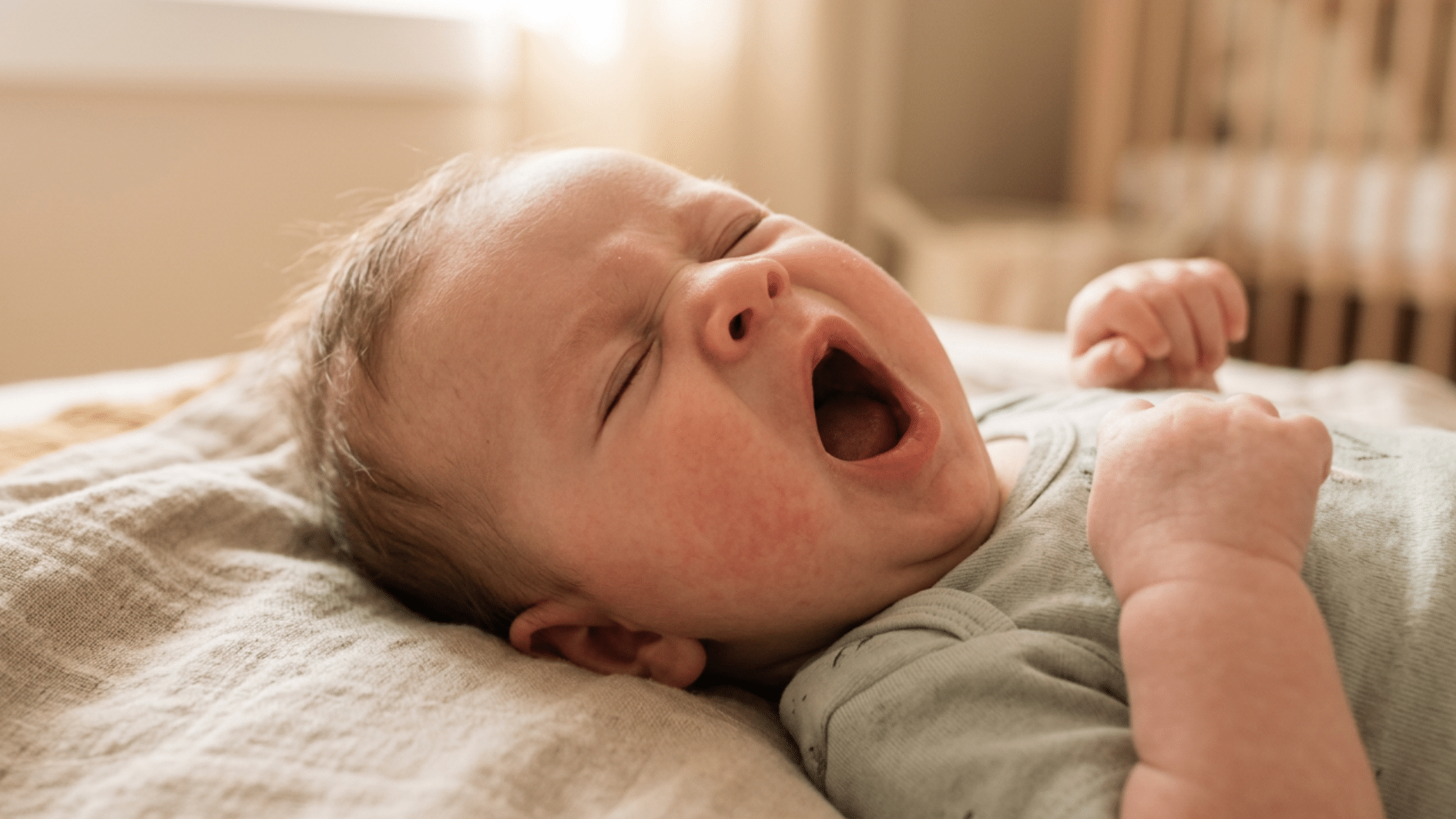 baby yawning while lying on a bed
