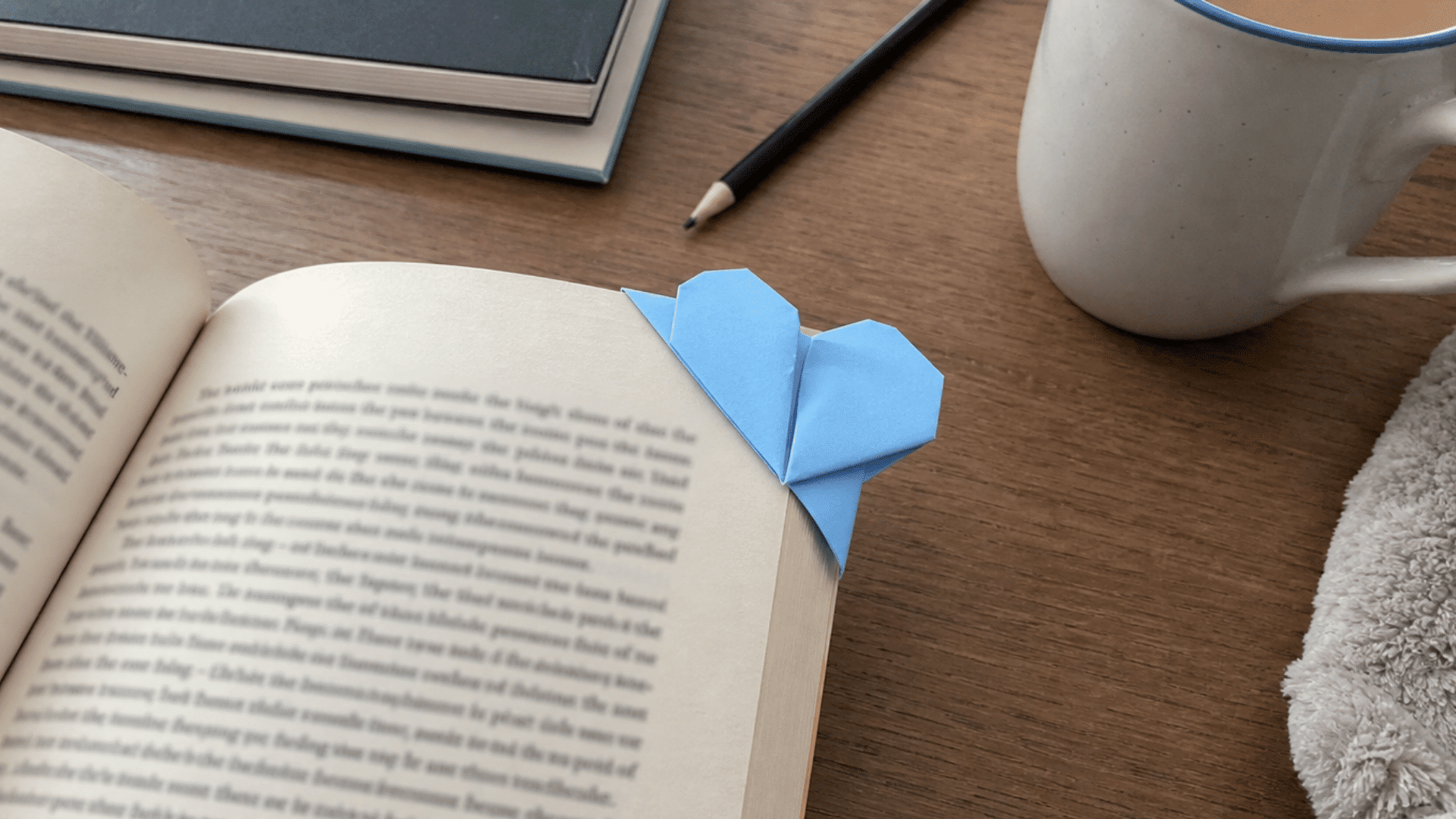 blue paper heart corner bookmark attached to the page corner of an open book