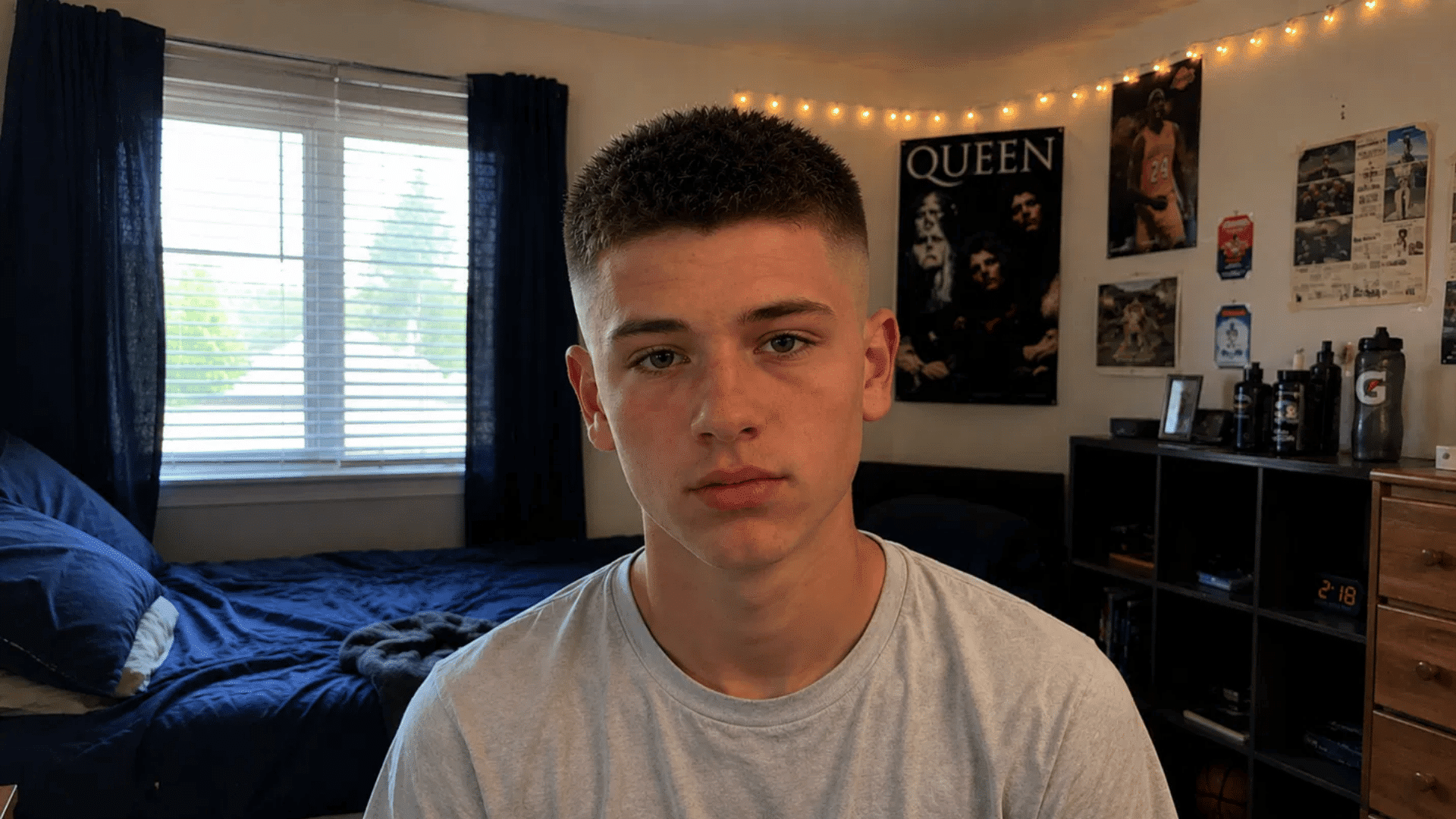 boy displaying crew cut with high skin fade haircut standing in bedroom decorated with string lights