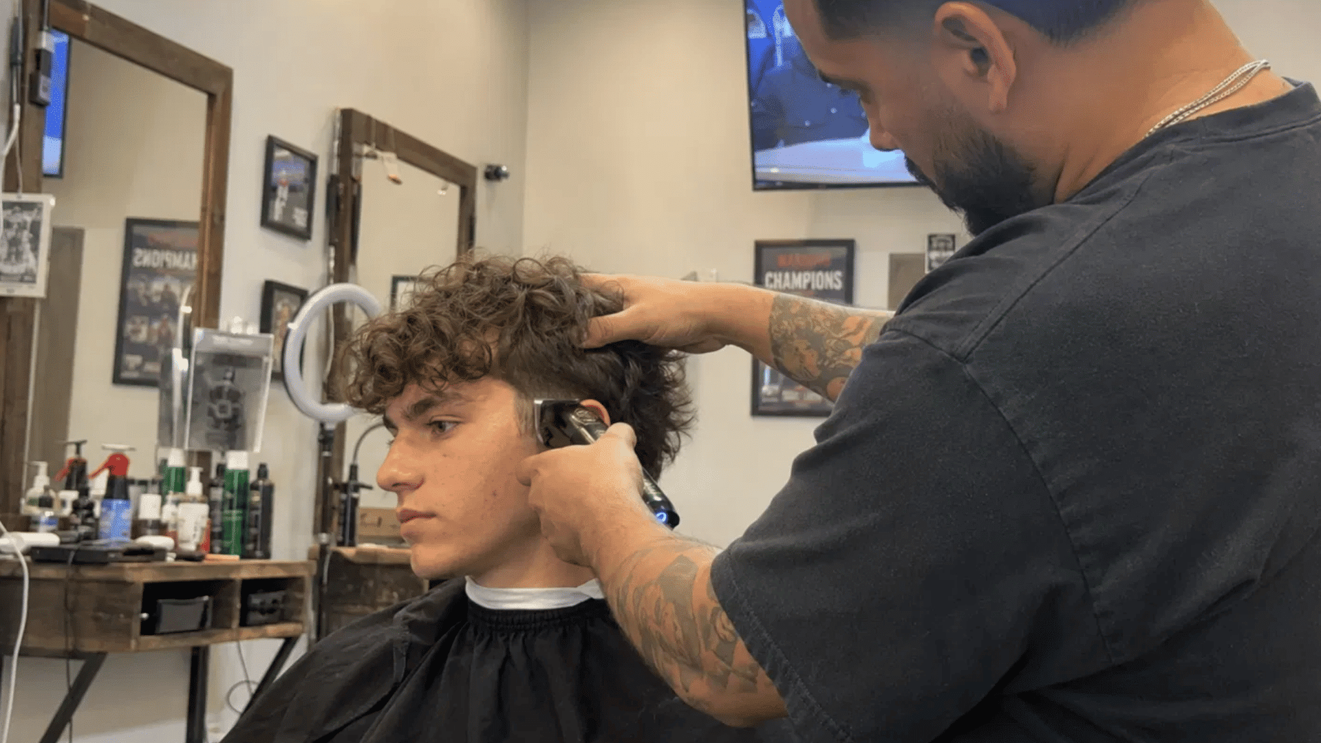 boy getting his curly hair trimmed by a barber, part of a blog on teenage boy haircuts