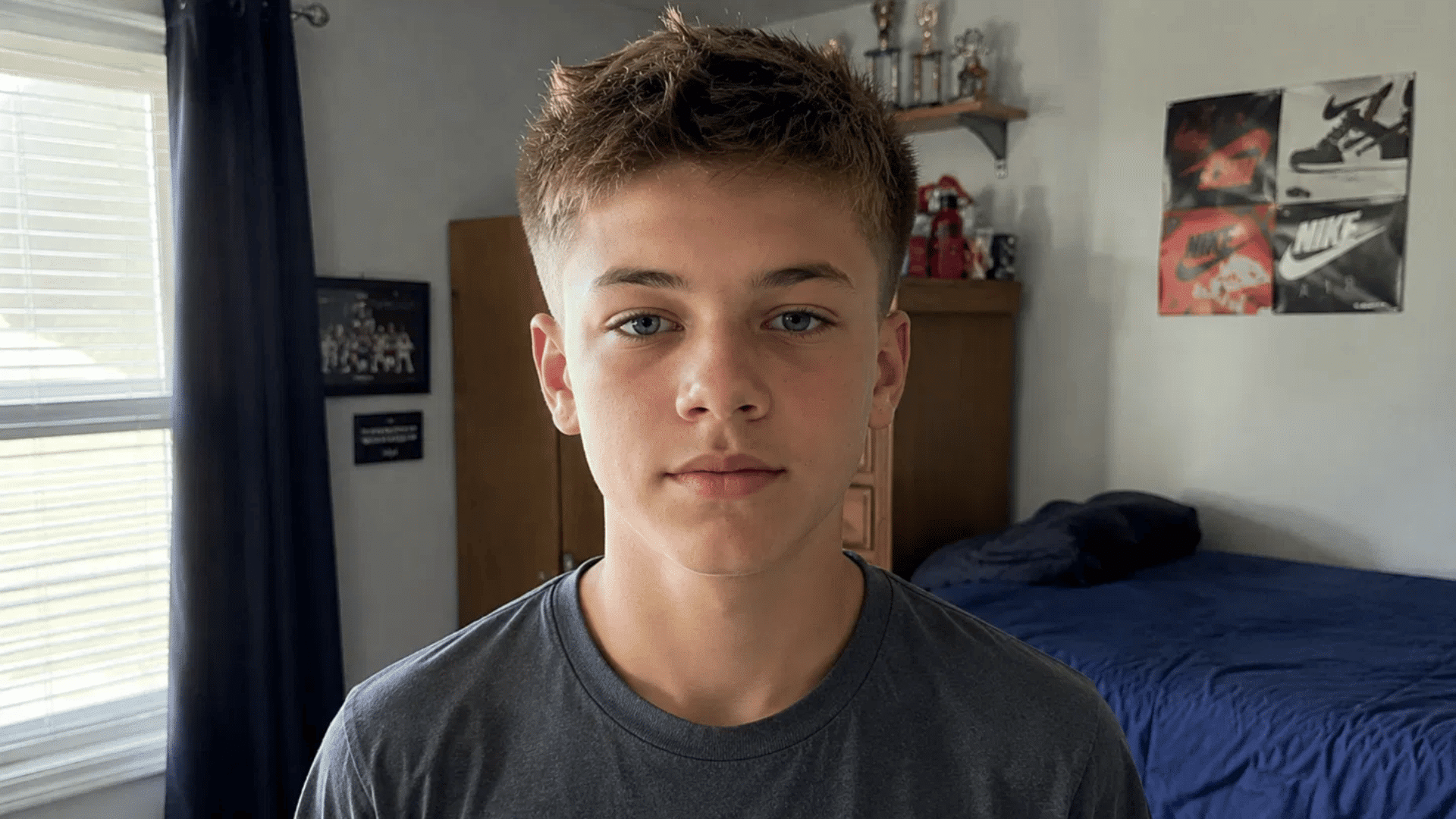 boy with textured crew cut and light spikes hairstyle posing in bedroom near window and trophies