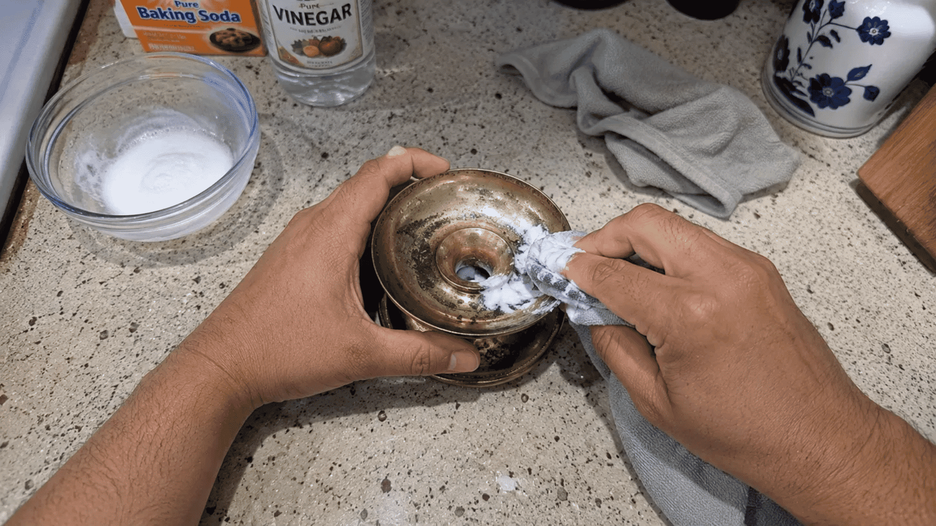 hands applying baking soda and vinegar paste to a brass item with a cloth