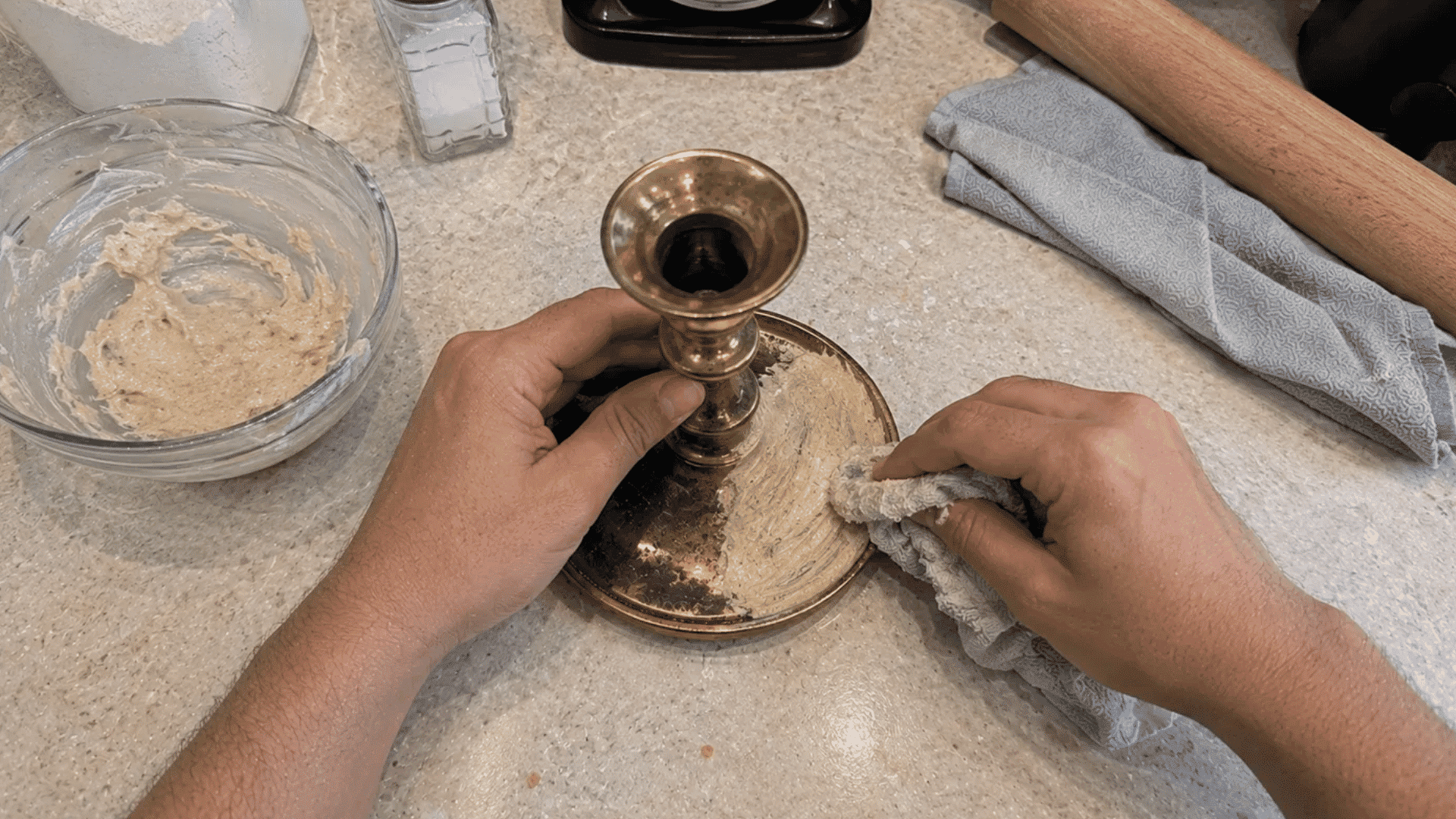 hands spreading a flour, salt, and vinegar paste on a brass candlestick