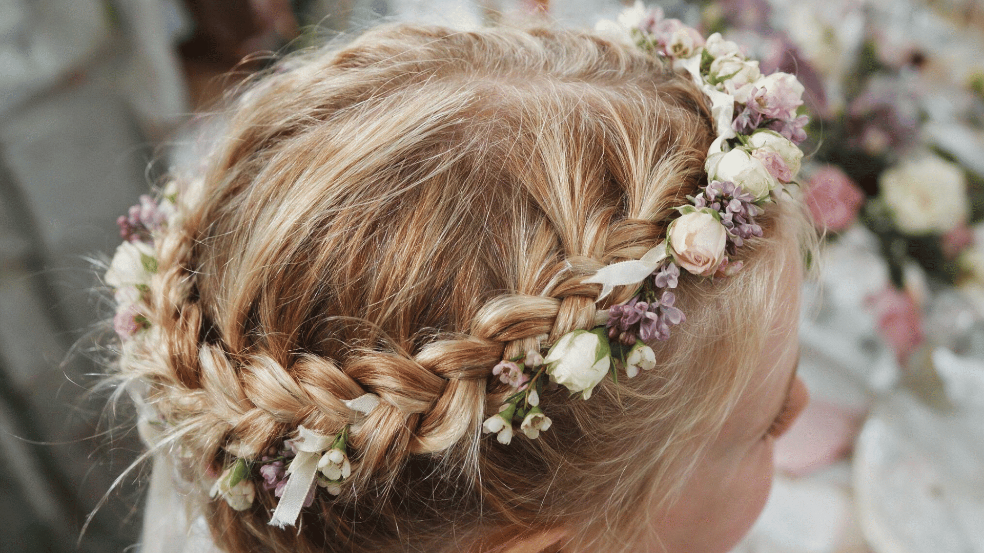 little girl with a braided floral crown hairstyle decorated with delicate fresh flowers for a special occasion or wedding celebration