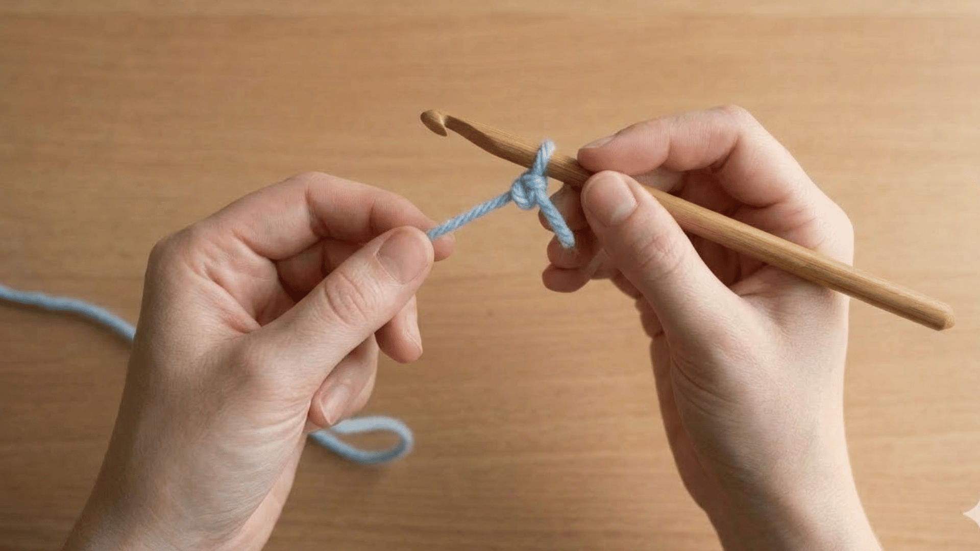 hands tightening a slip knot loop onto a wooden crochet hook