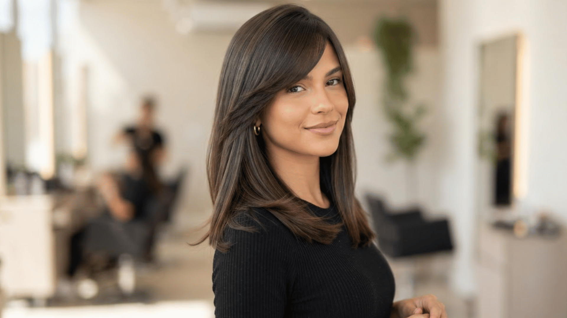 medium length haircut with side swept bangs and smooth layers styled in salon setting with natural texture and shine