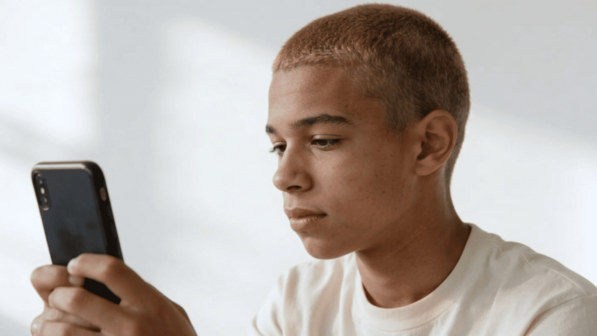 profile of a boy with a short buzz cut, even clipped hair and warm light