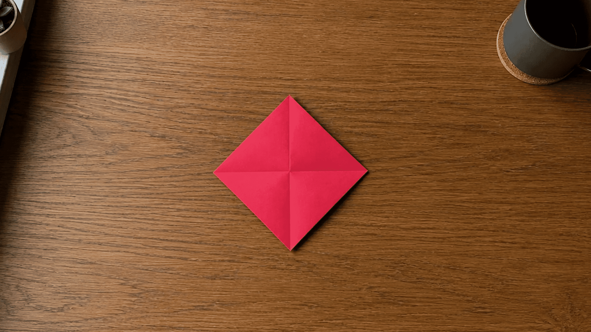 red paper folded into a diamond shape for step 3 of an origami heart