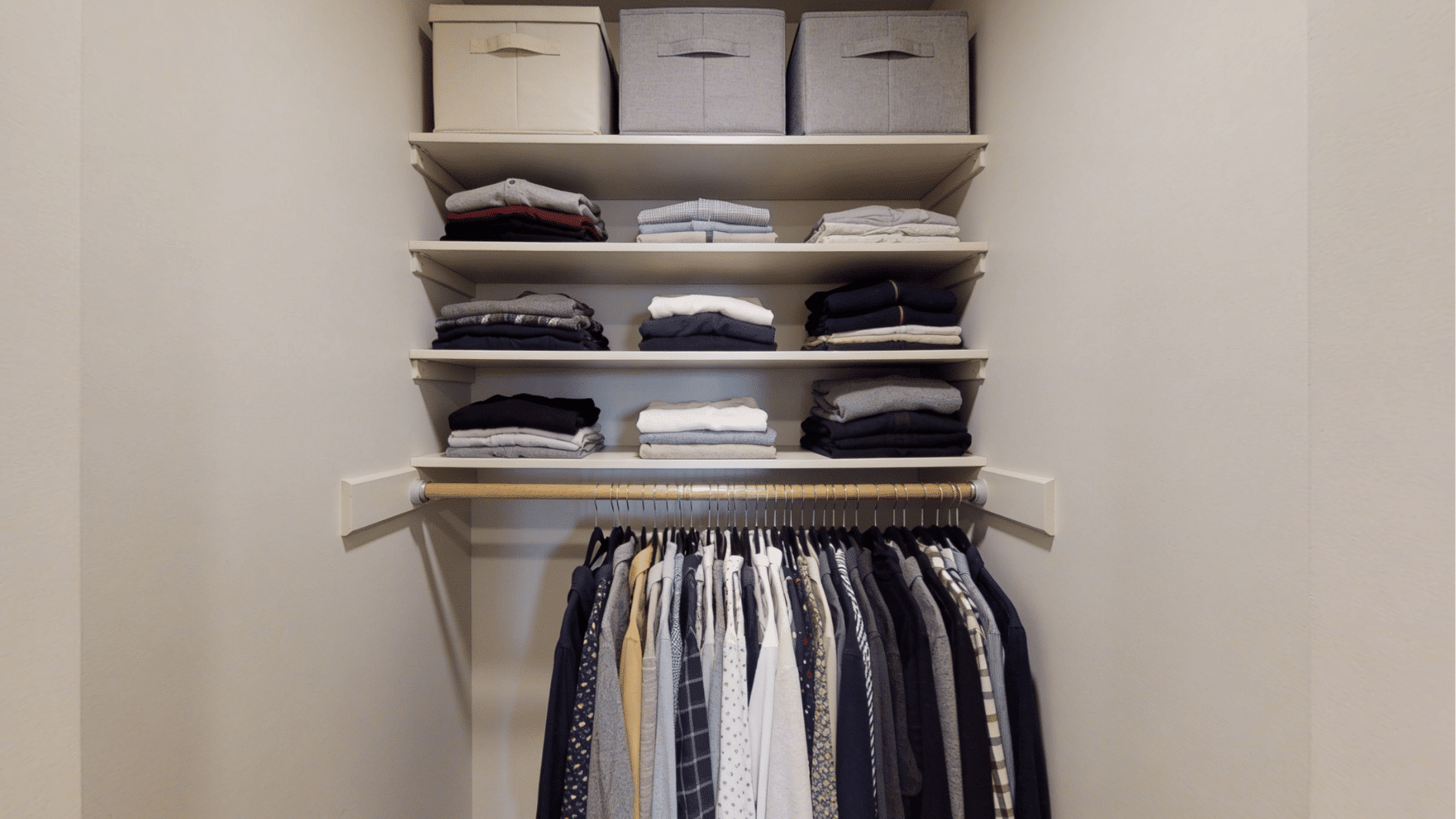 shelf and rod combination closet organizer with folded clothes on shelves and hanging garments below