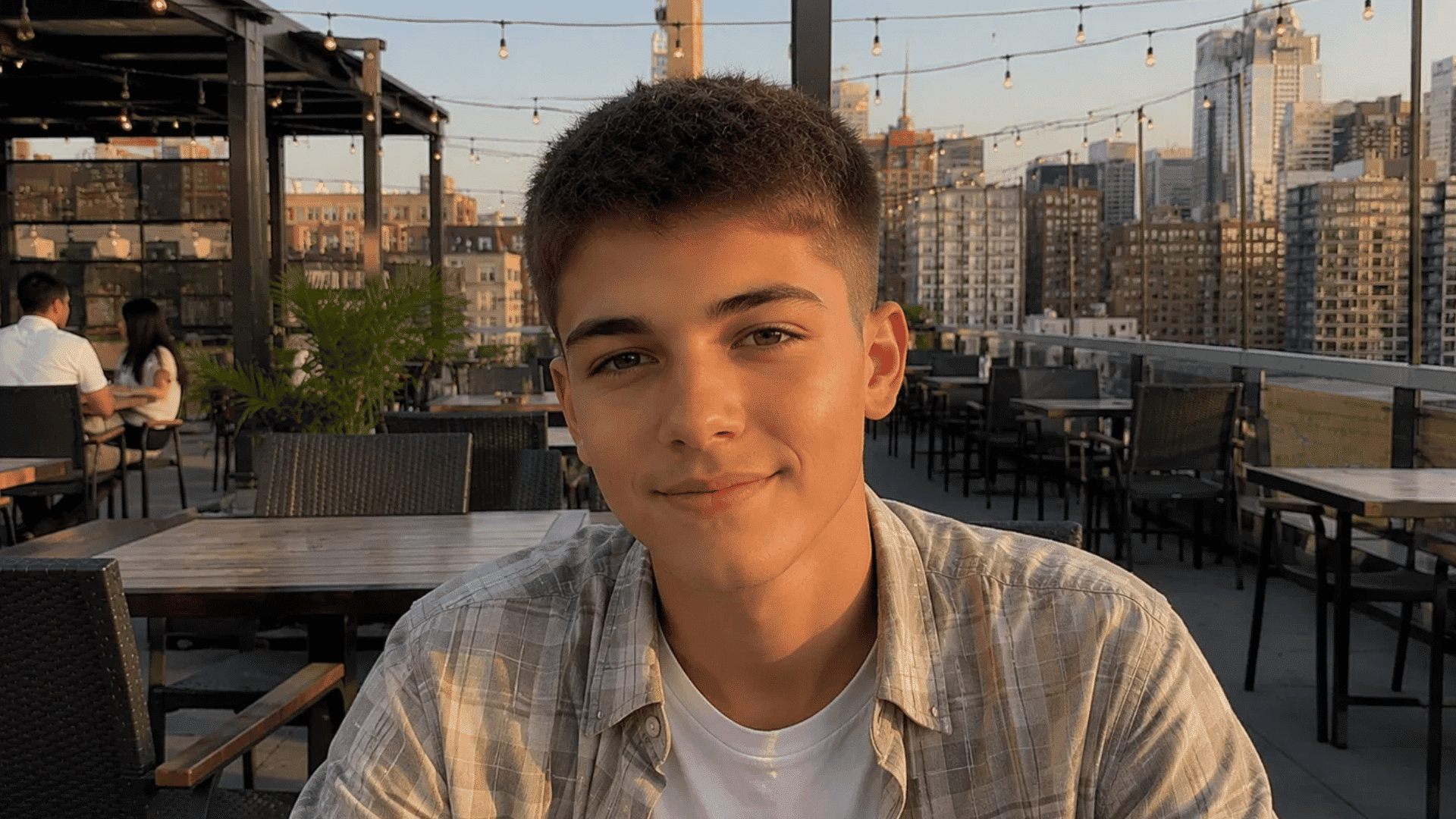 smiling teen with crew cut matte texture cream finish hairstyle on rooftop with city skyline view