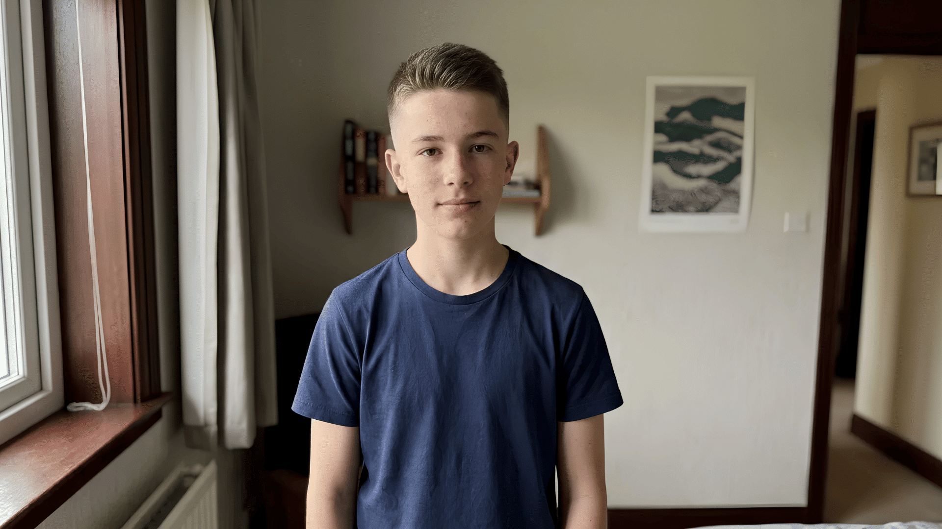 teen boy in navy blue tshirt with classic crew cut and even taper haircut standing in bedroom near window