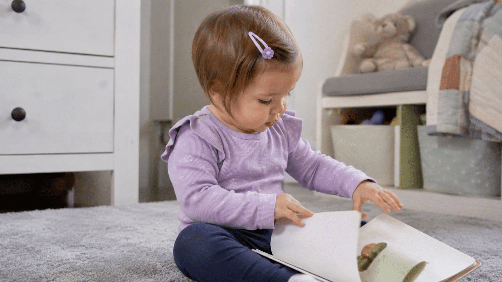 toddler girl reading a book while showing a cute side swept clip hairstyle in a cozy room