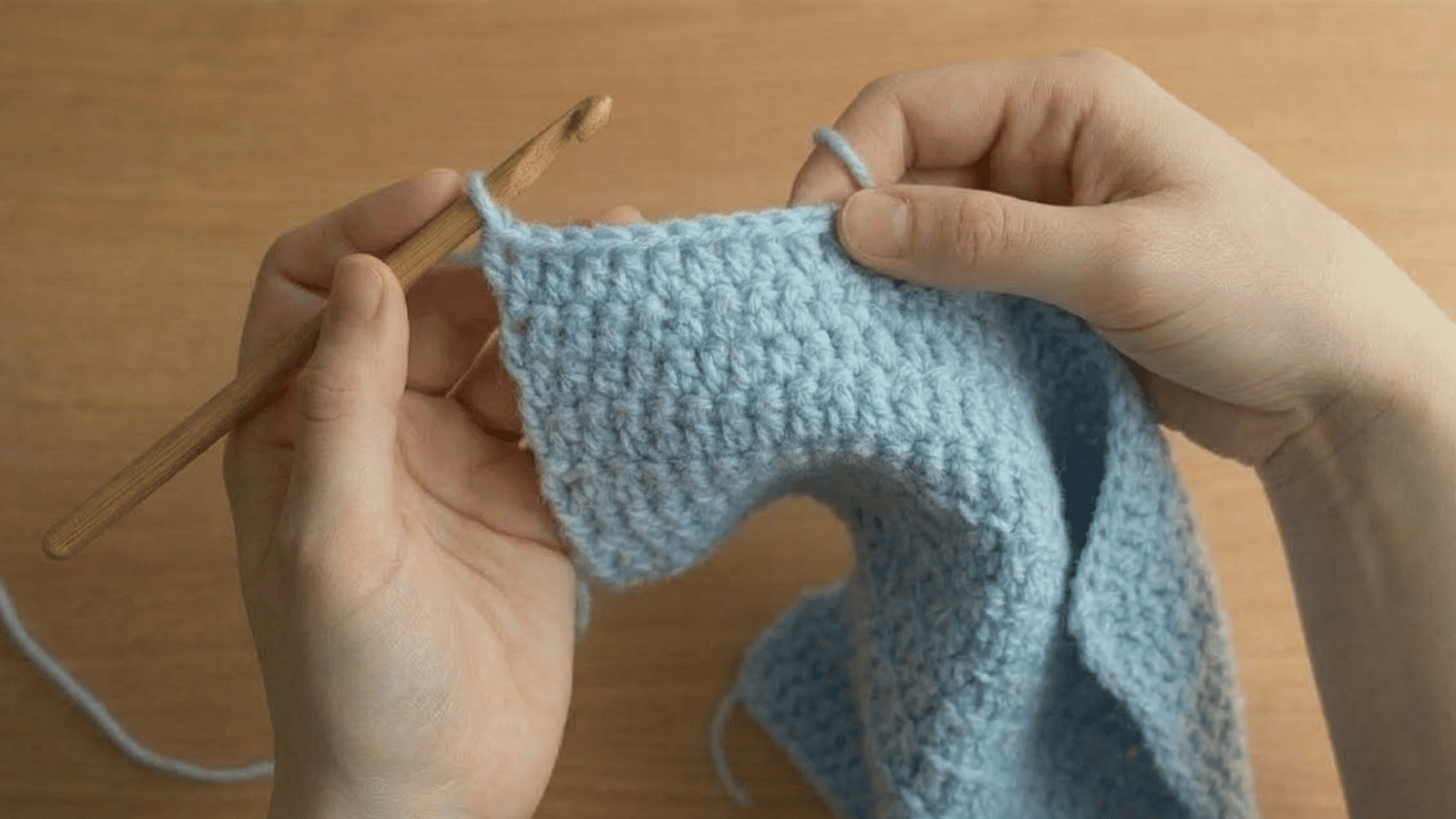 hands turning a light blue crochet swatch to start row two