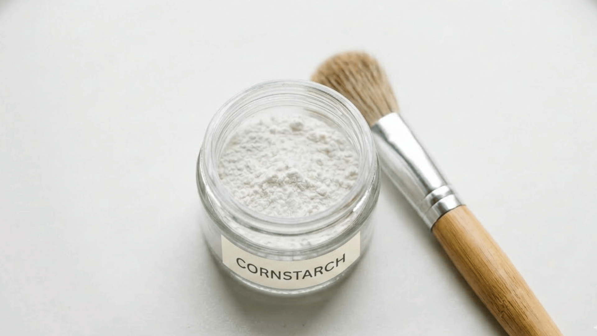 woman applying cornstarch dry shampoo powder to hair roots