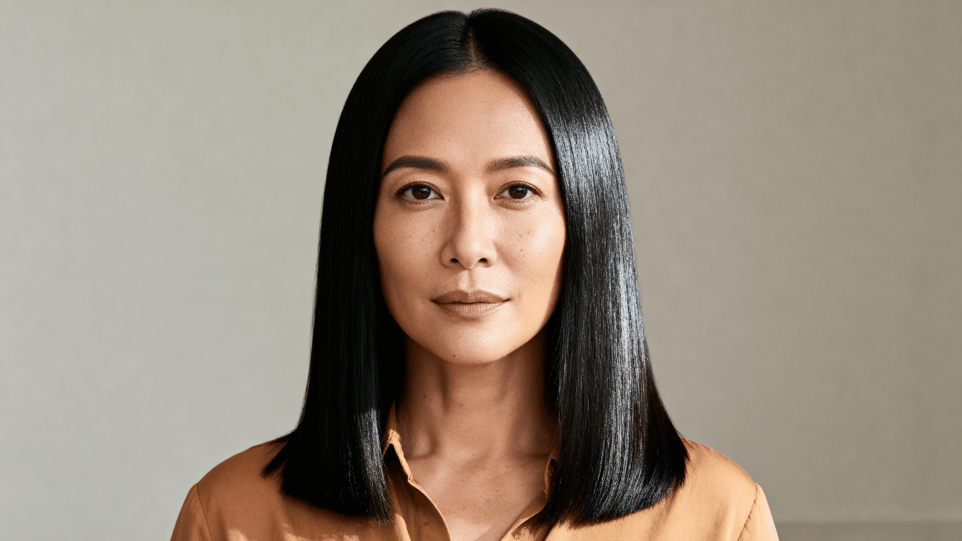 woman with fine straight black hair styled in a sleek medium-length haircut featuring a natural glossy finish and shine