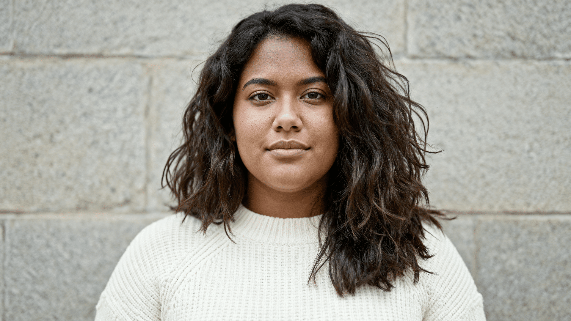 woman  with thick wavy dark brown hair styled in a choppy layered medium-length haircut featuring natural texture