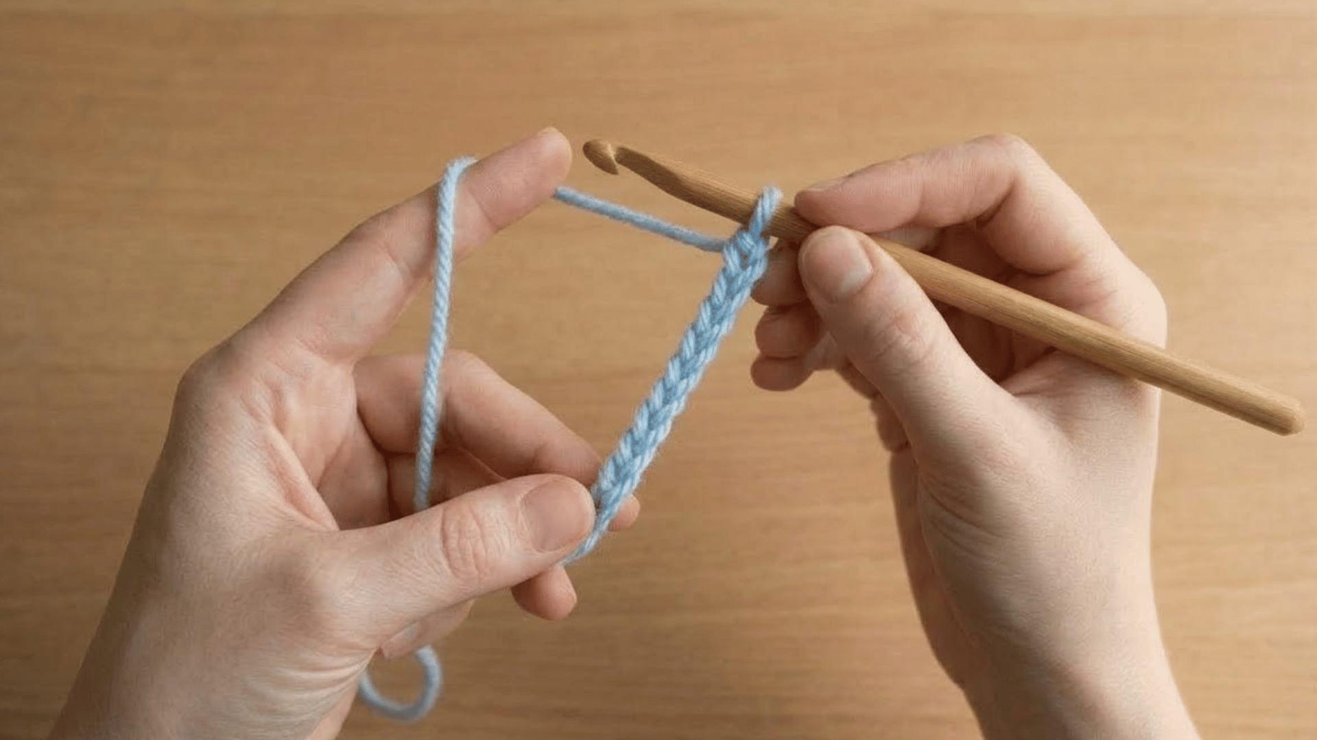 hands working a light blue foundation chain with a crochet hook