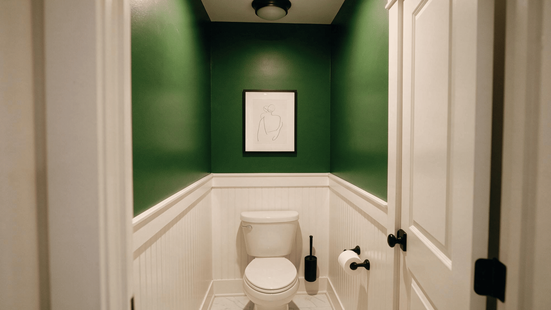 small half bathroom with white beadboard wainscoting, green accent wall, and framed art above the toilet