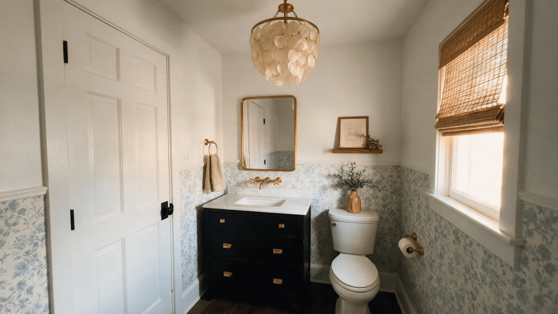 small black-and-white half bathroom with floral wallpaper, dark vanity, and a brass capiz-shell chandelier