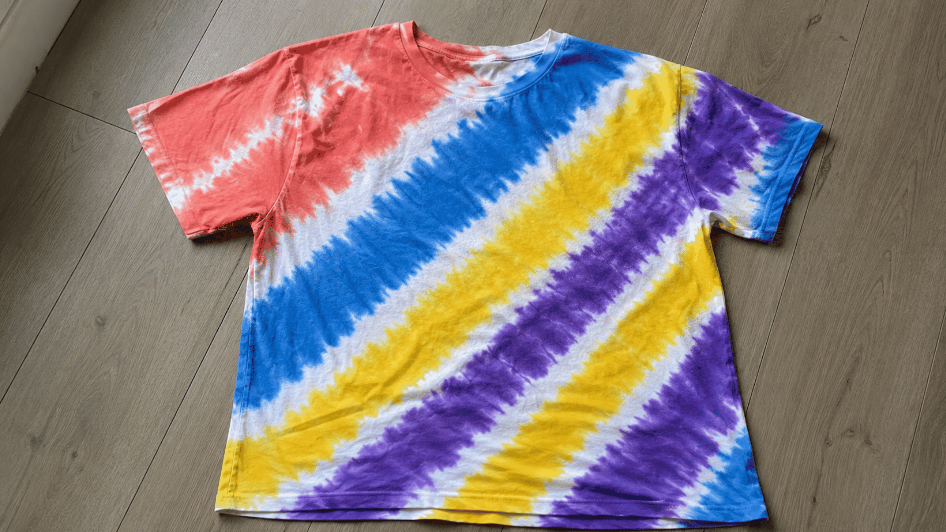 colorful diagonal stripe tie dye pattern across a white cotton t shirt