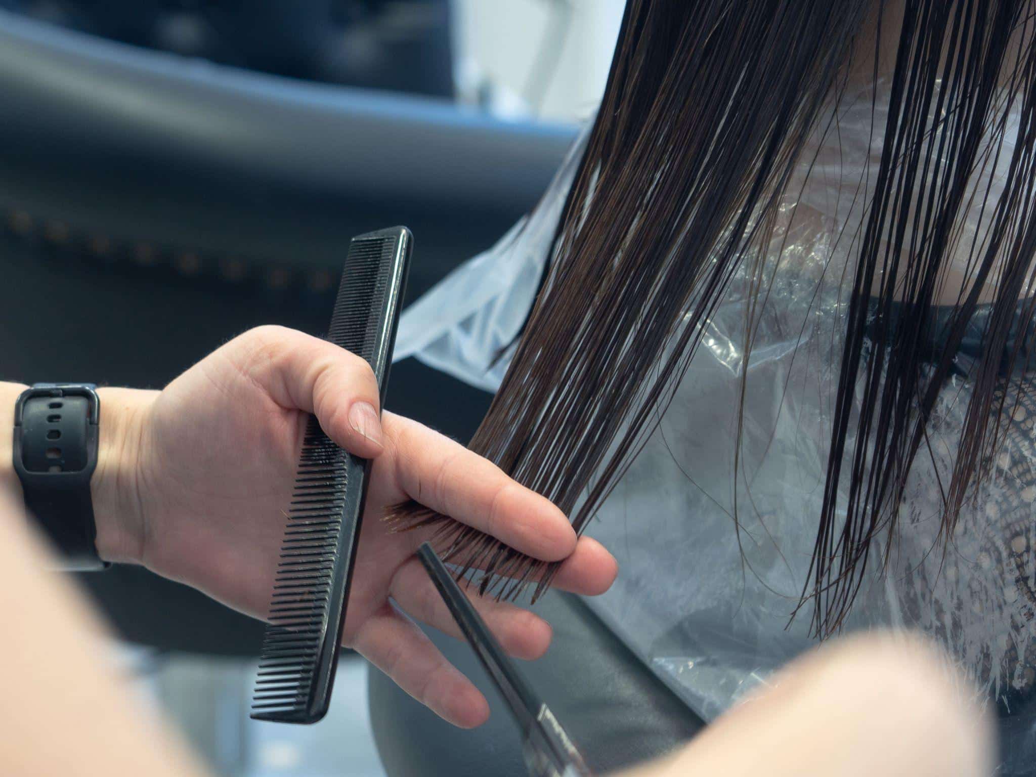 Hair being trimmed with scissors and comb in modern salon setting