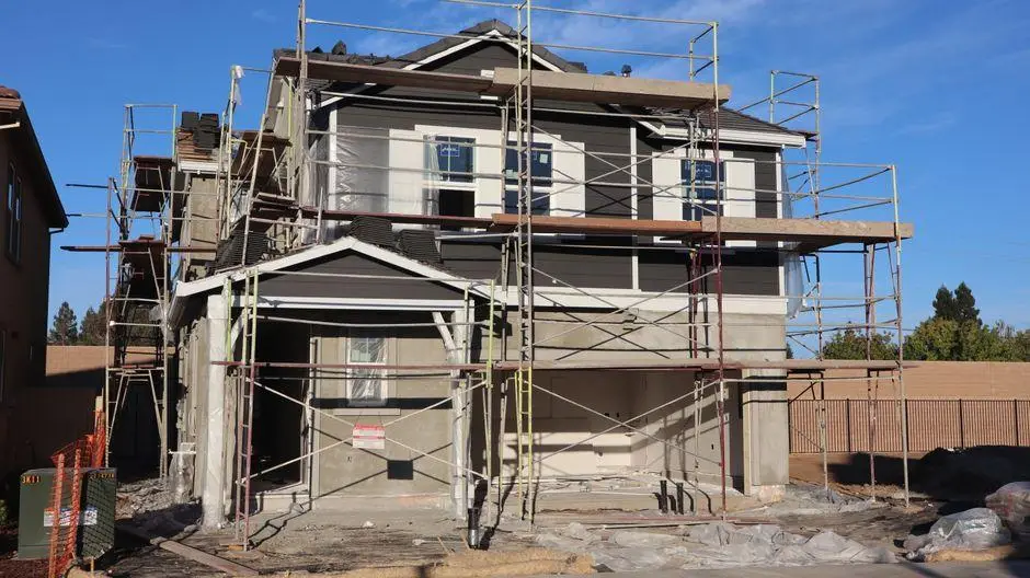 Two-story house under construction with scaffolding in an outdoor residential area