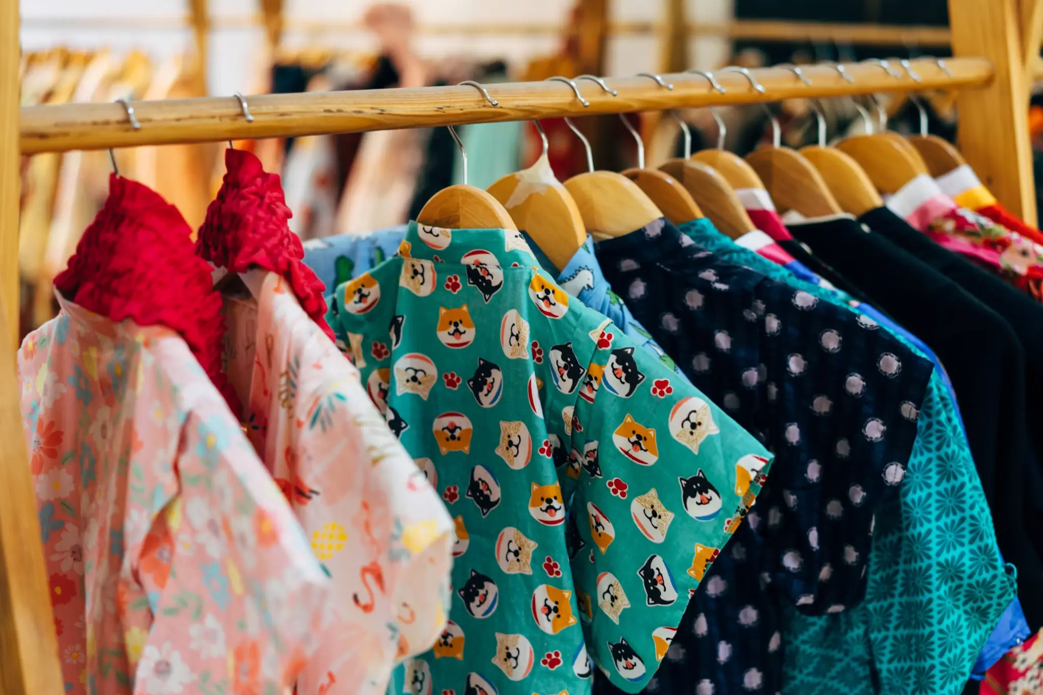 Colorful patterned shirts hanging on wooden clothing rack in a retail store setting