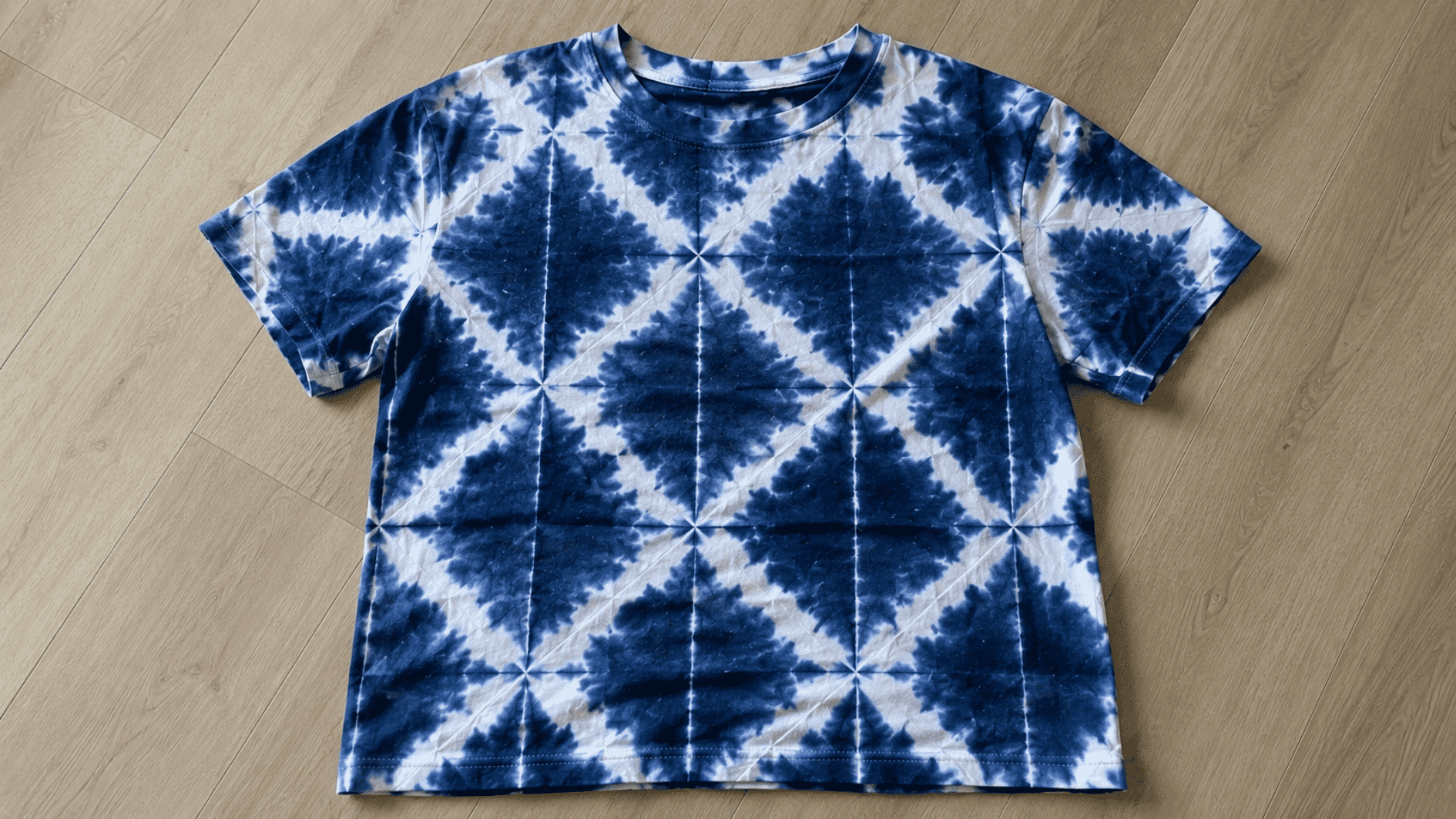 indigo shibori tie dye pattern with geometric resist marks on a cotton t shirt