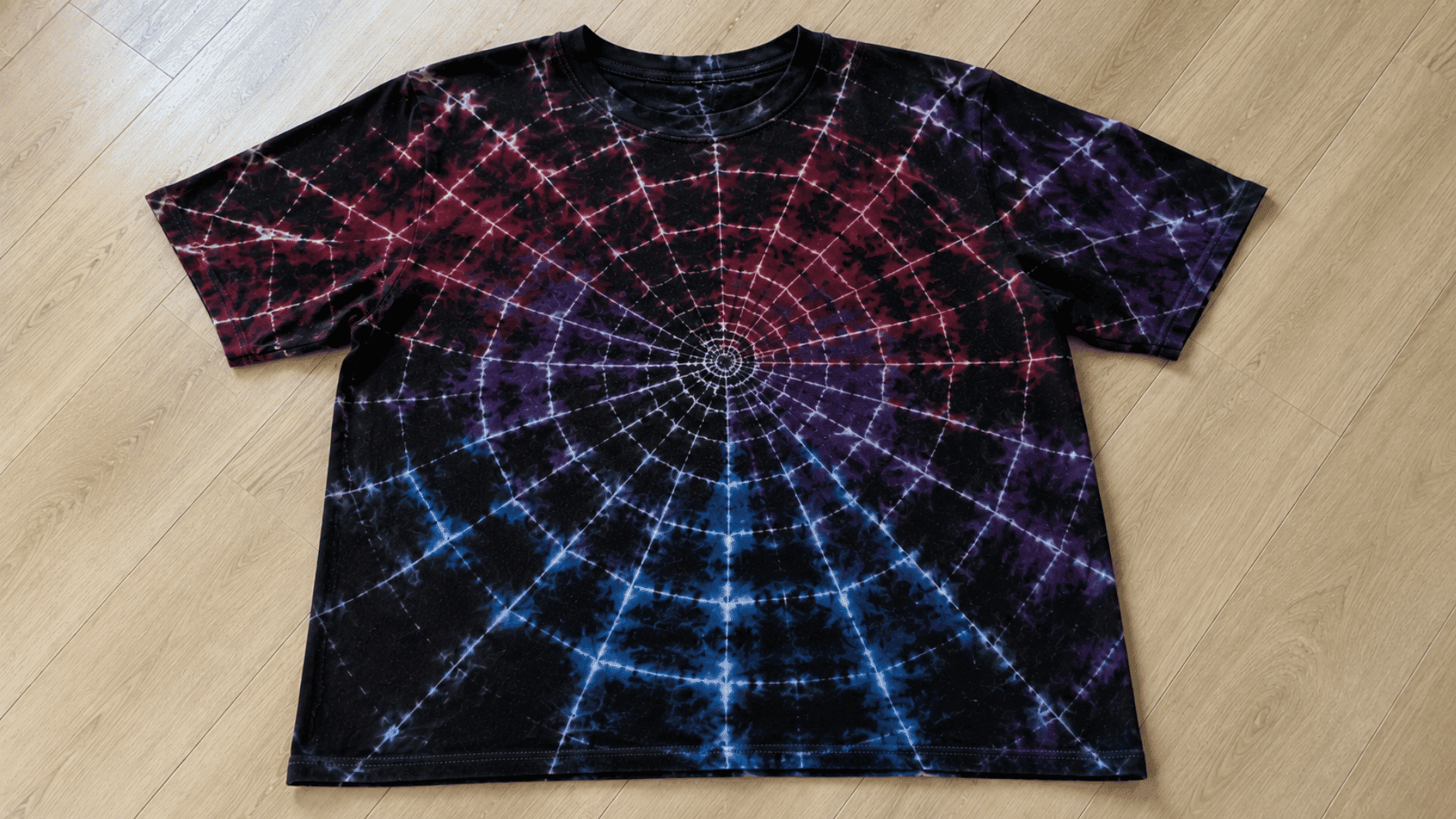 red blue and purple spider tie dye pattern with web like lines on a t shirt