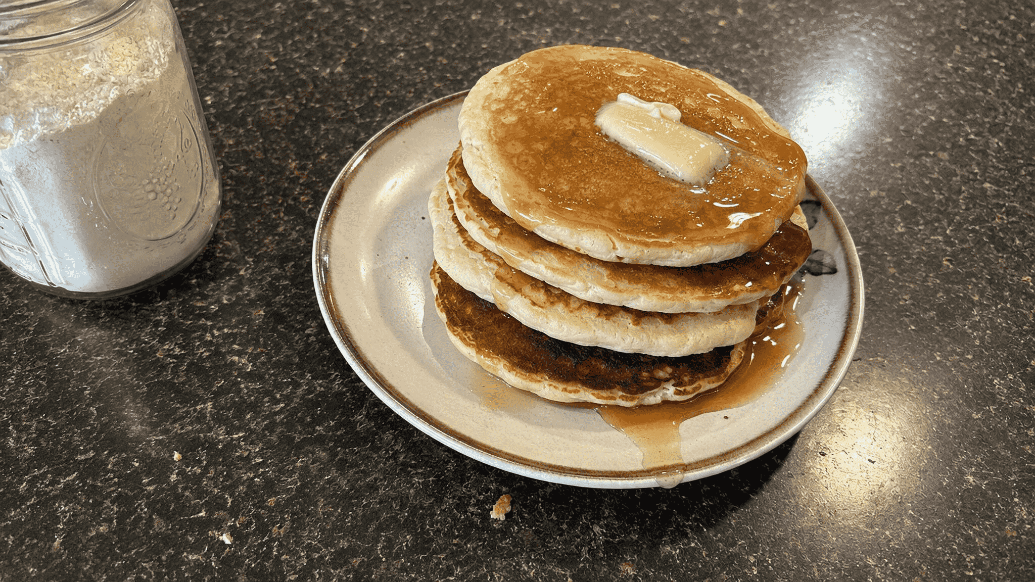stack of warm homemade pancakes topped with melting butter and maple syrup.