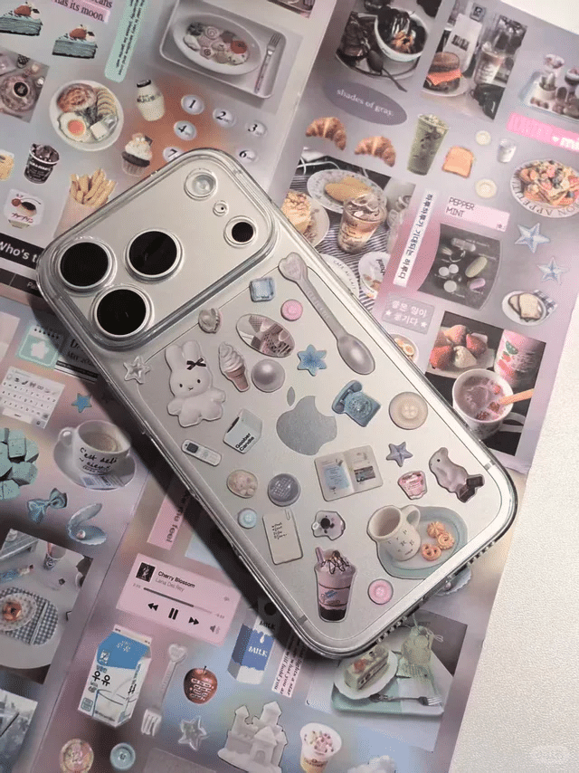 Silver smartphone with cute pastel stickers on case resting on colorful magazine pages