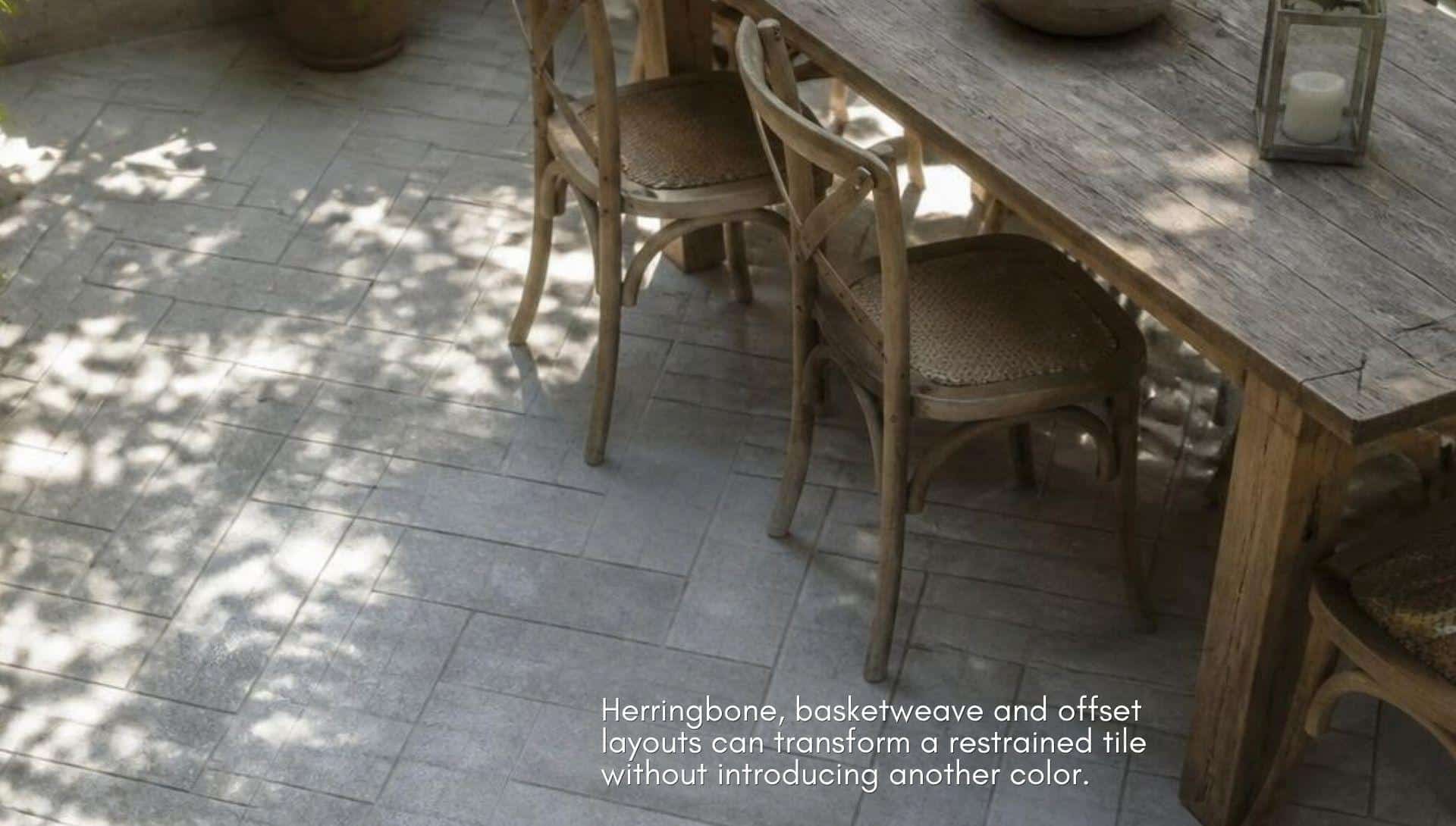 Rustic wooden dining table and chairs on herringbone tile patio with dappled sunlight